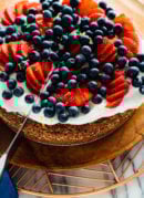 slicing lemon almond cake with berries on top-4